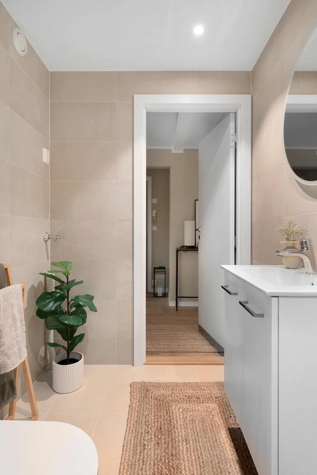Badet har beige fliser på gulv og vegg Galleribilde