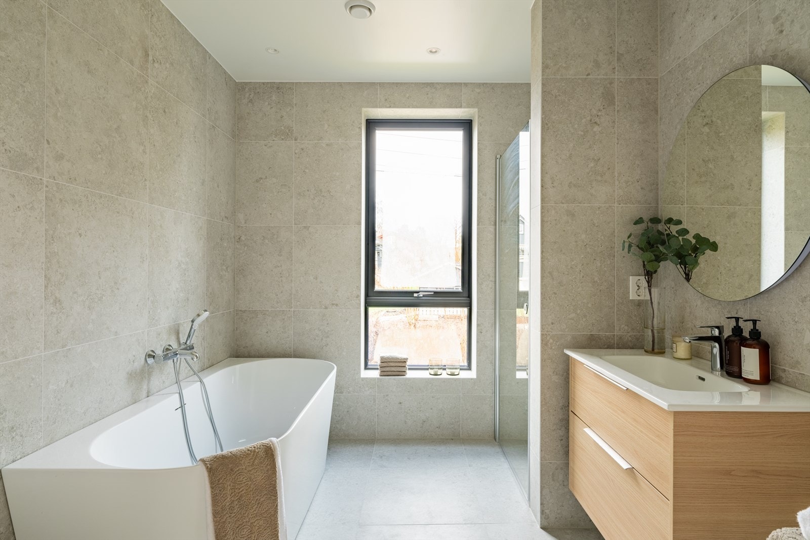 Boligens andre bad er moderne og gjennomført, med flislagte flater i tidløse fargetoner som gir et elegant og helhetlig uttrykk. Galleribilde