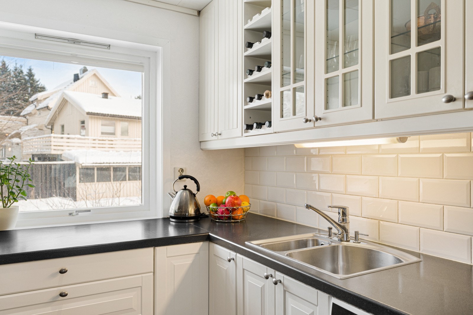 Kjøkkeninnredningen inkluderer praktiske løsninger som vitrineskap og vinhylle. Galleribilde