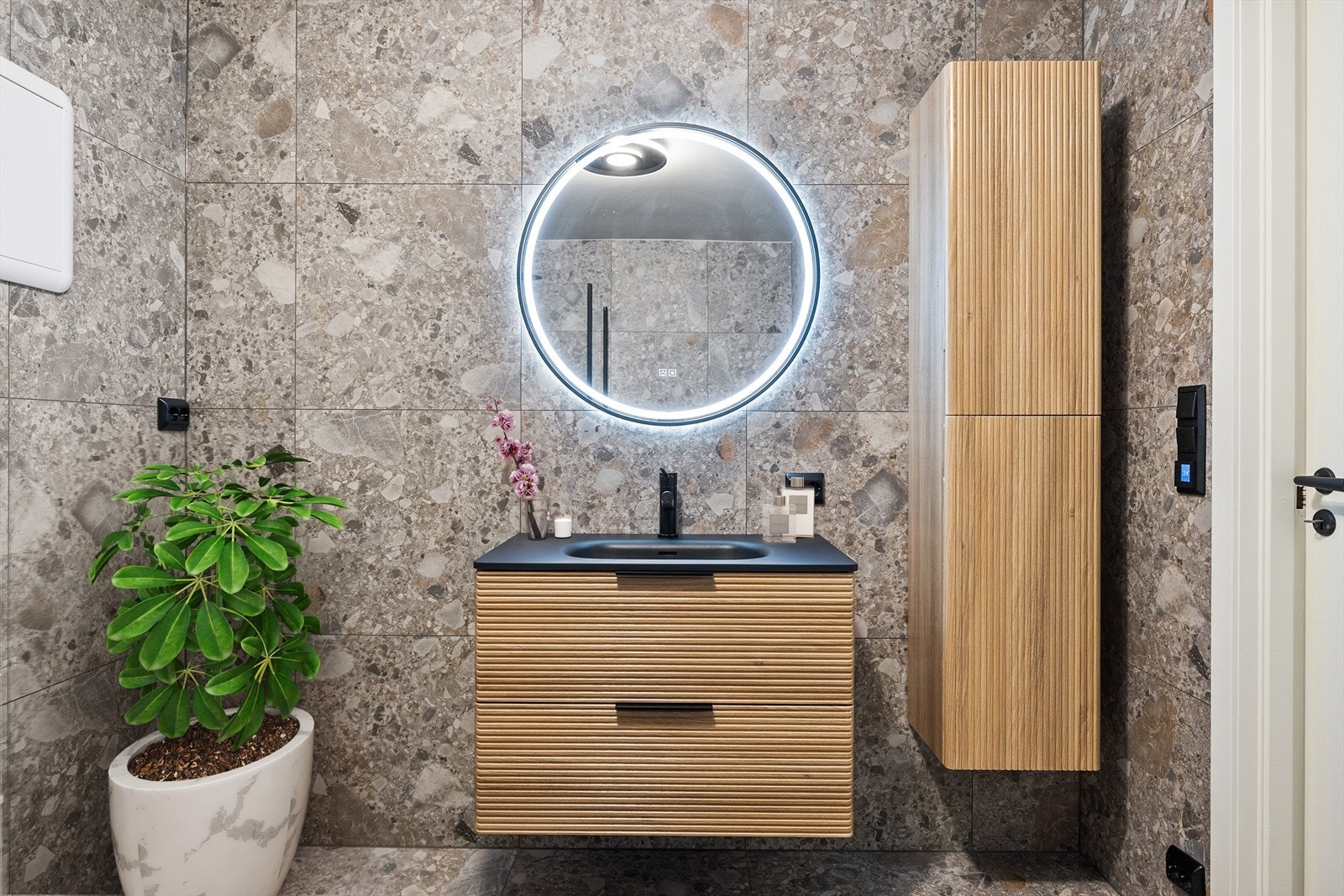 Rommet er innredet med dusjhjørne. servantskap, speil med lys, høyskap, opplegg til vaskemaskin og vegghengt klosett. Galleribilde