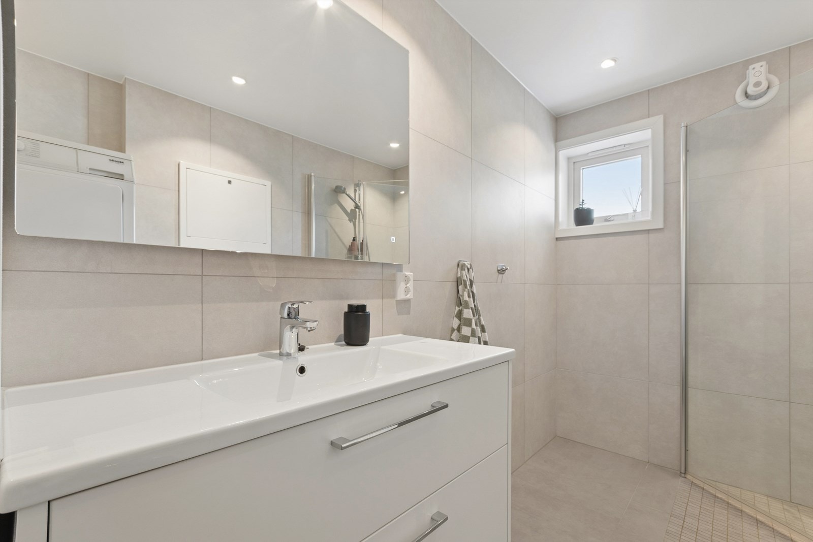 Videre har badet 60x60 flis på vegger og gulv, lun gulvvarme, 6 downlights i taket og opplegg for vaskemaskin. Galleribilde