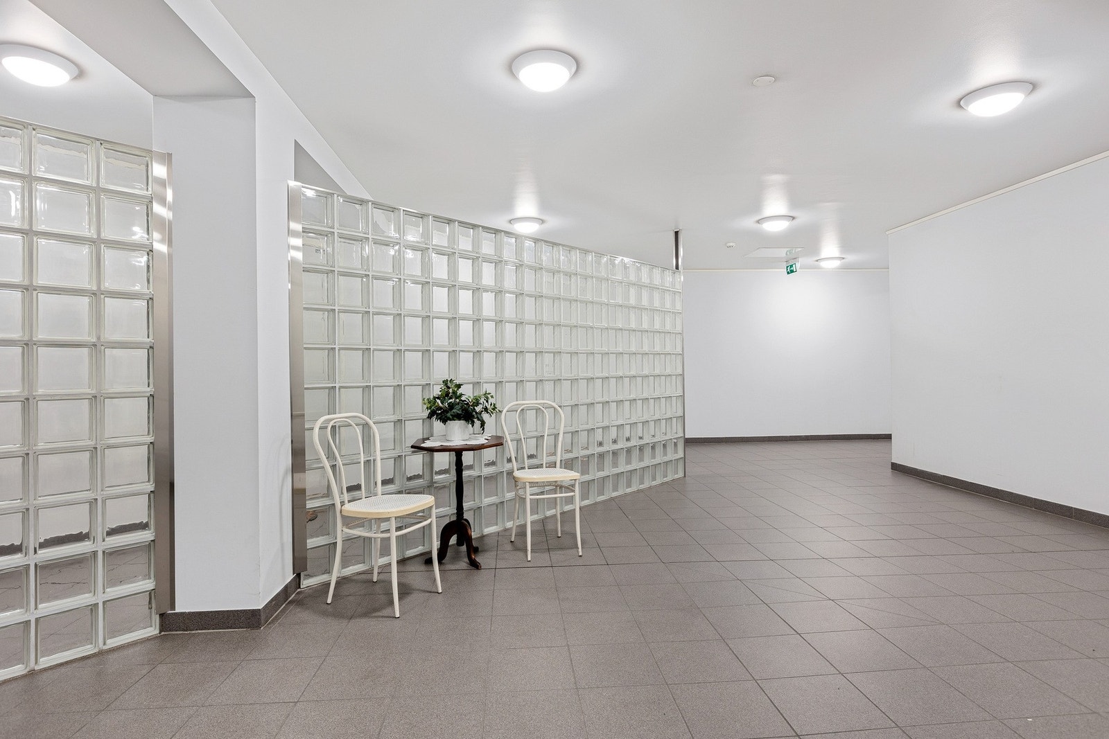 Lyst og romslig fellesareal med flislagt gulv og dekorativ glassvegg. Galleribilde