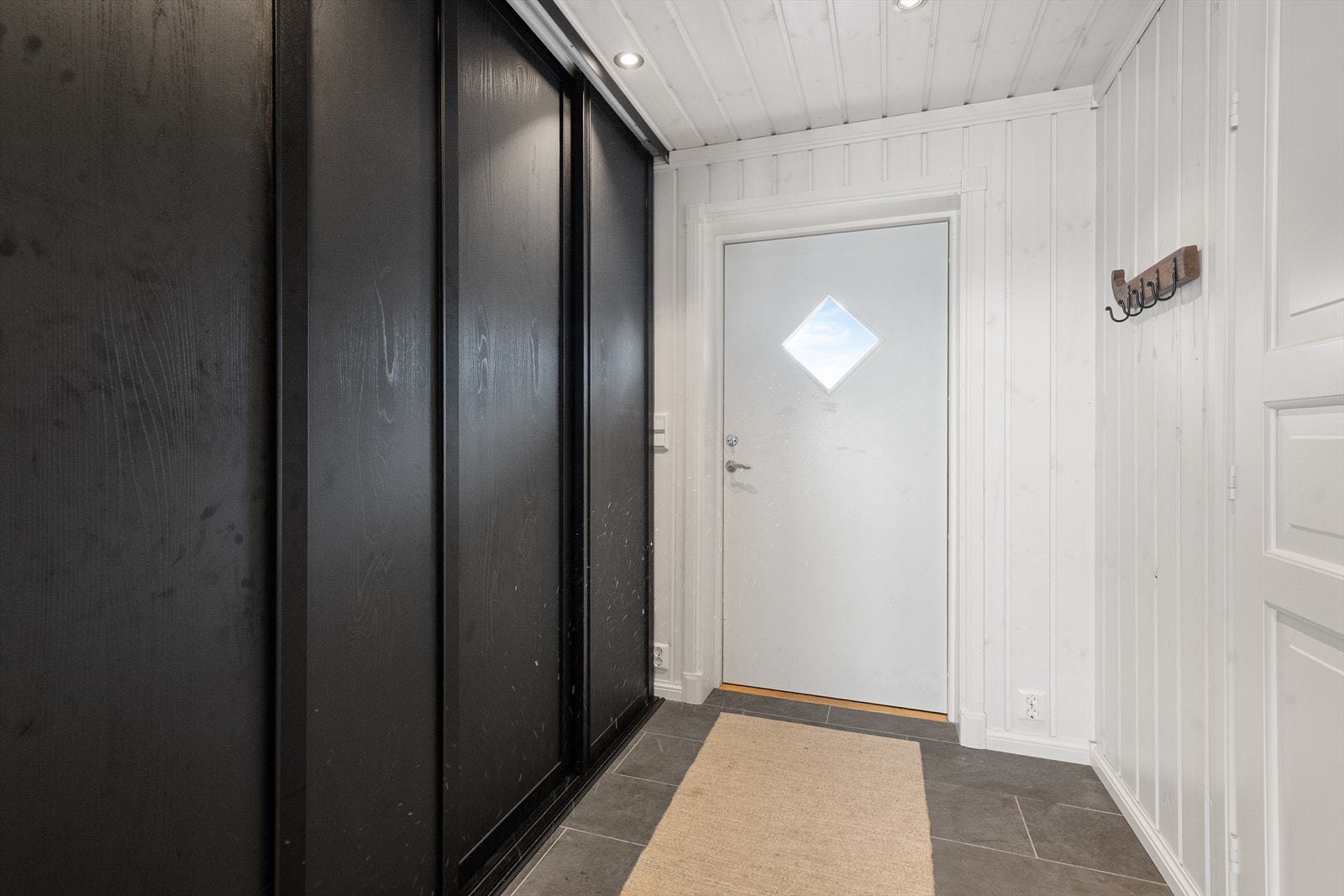 Hyggelig entre som ønsker velkommen inn i hytta, hvor det er plass til sko og yttertøy i romslige skap med skyvedører. Galleribilde