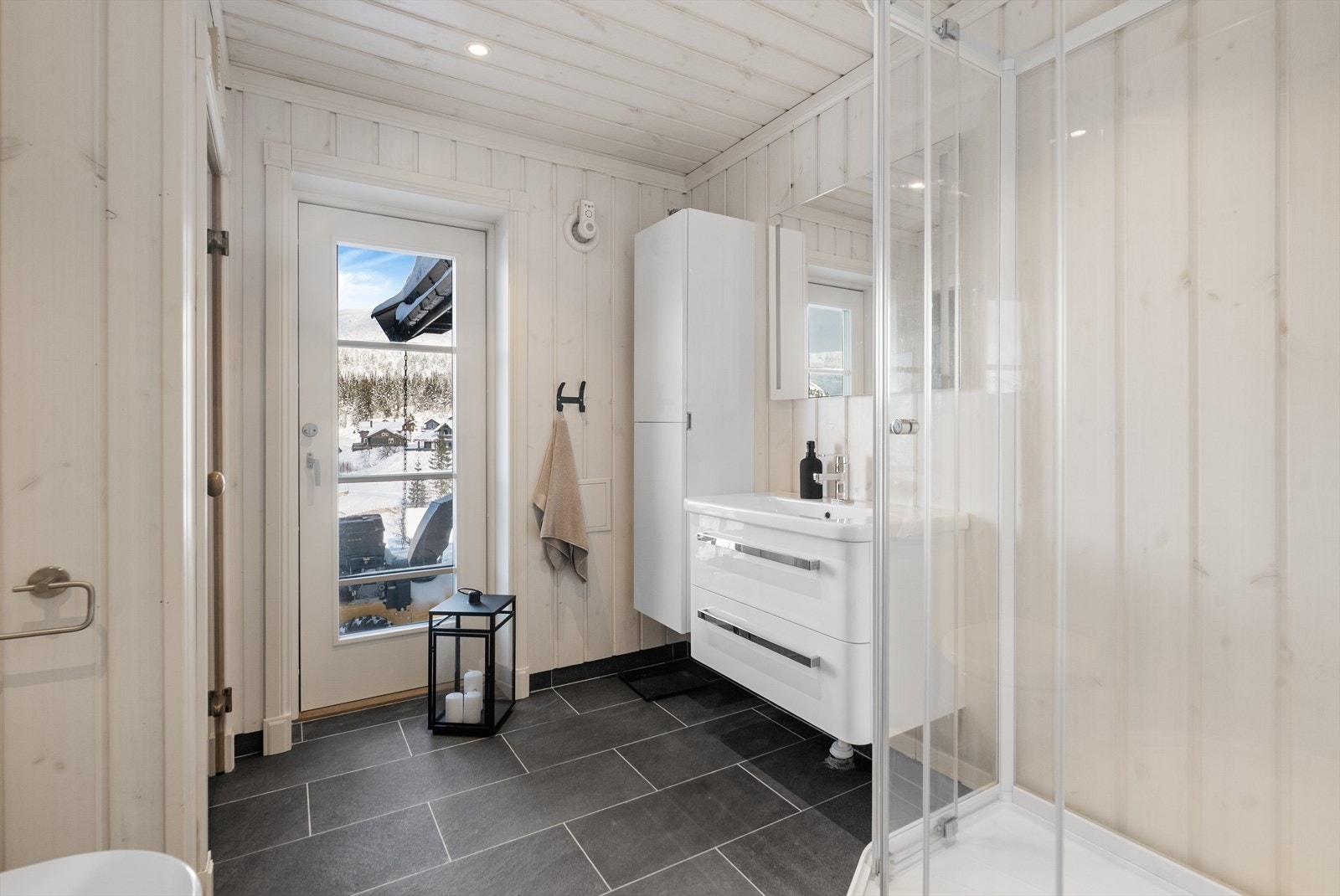 Hytta har to romslige bad med flis og varmekabler på gulv, panel på vegger og panel i tak med innfelte spotter. Galleribilde