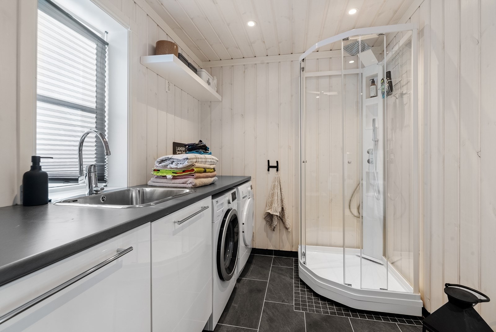 Badet ved entre inneholder toalett, dusjkabinett, skapinnredning med vaskekar og opplegg til vaskemaskin. Galleribilde