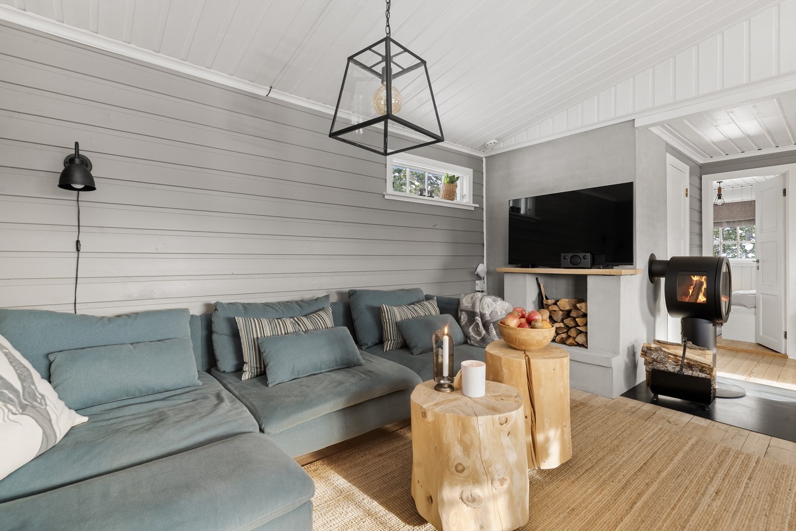 Stuen er romslig og har plass til både sofagruppe og spisestuebord. Her er det et lekkert ildsted av type Nordpeis ME fra 2022. Pipen har ny feieluke, og slette pene overflater. Galleribilde