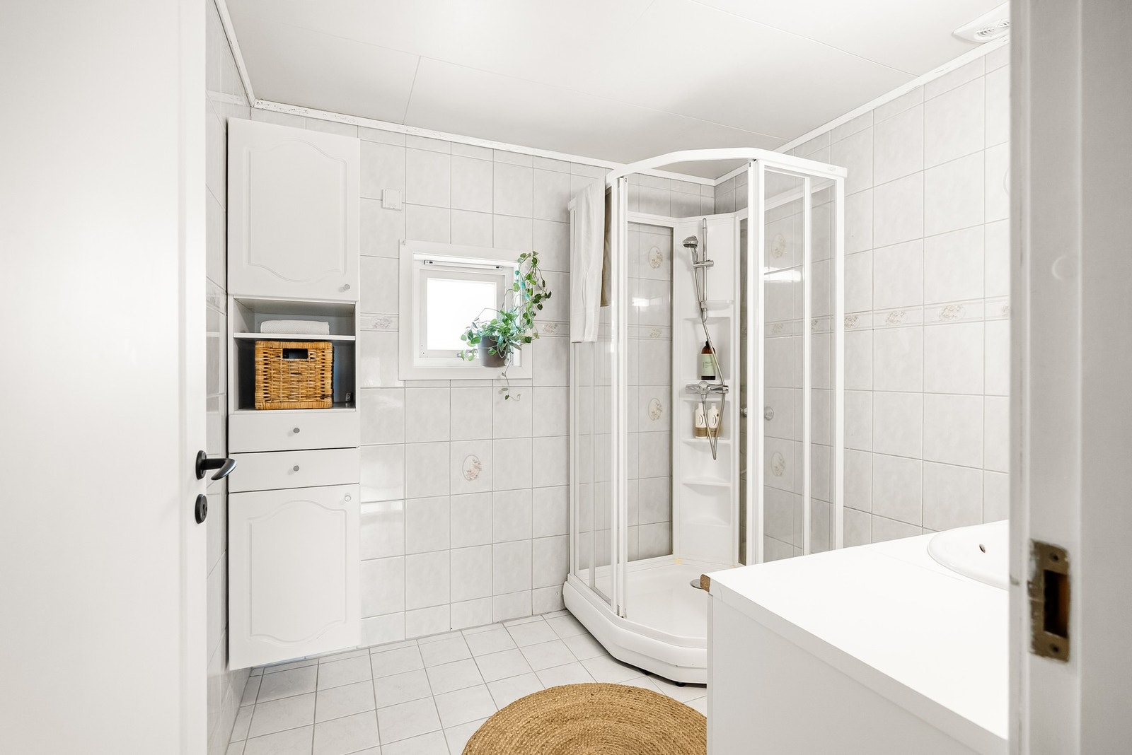 Badet er innredet med nedfelt servant, speil på vegg, høyskap og dusjkabinett. Galleribilde