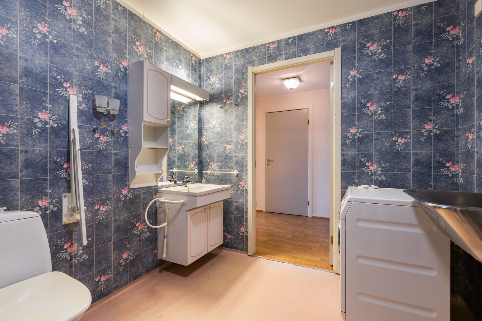 Baderommet har en fin størrelse med beige gulvbelegg og blå våtromstapet på veggene. Galleribilde