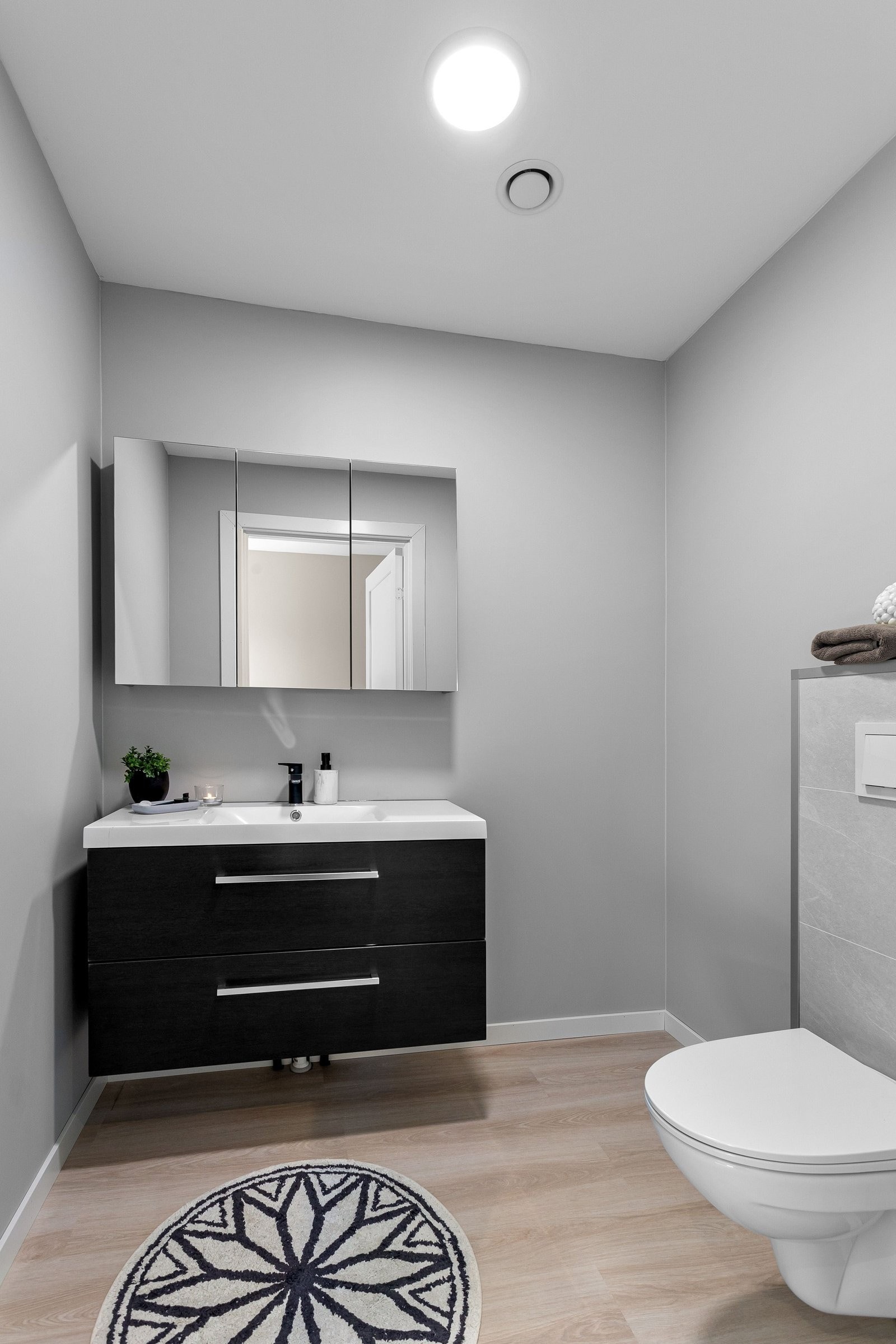 Strøkent ekstra toalettrom i 2. etasje med sort innredning, nedfelt servant, speil med skap og vegghengt toalett. Galleribilde