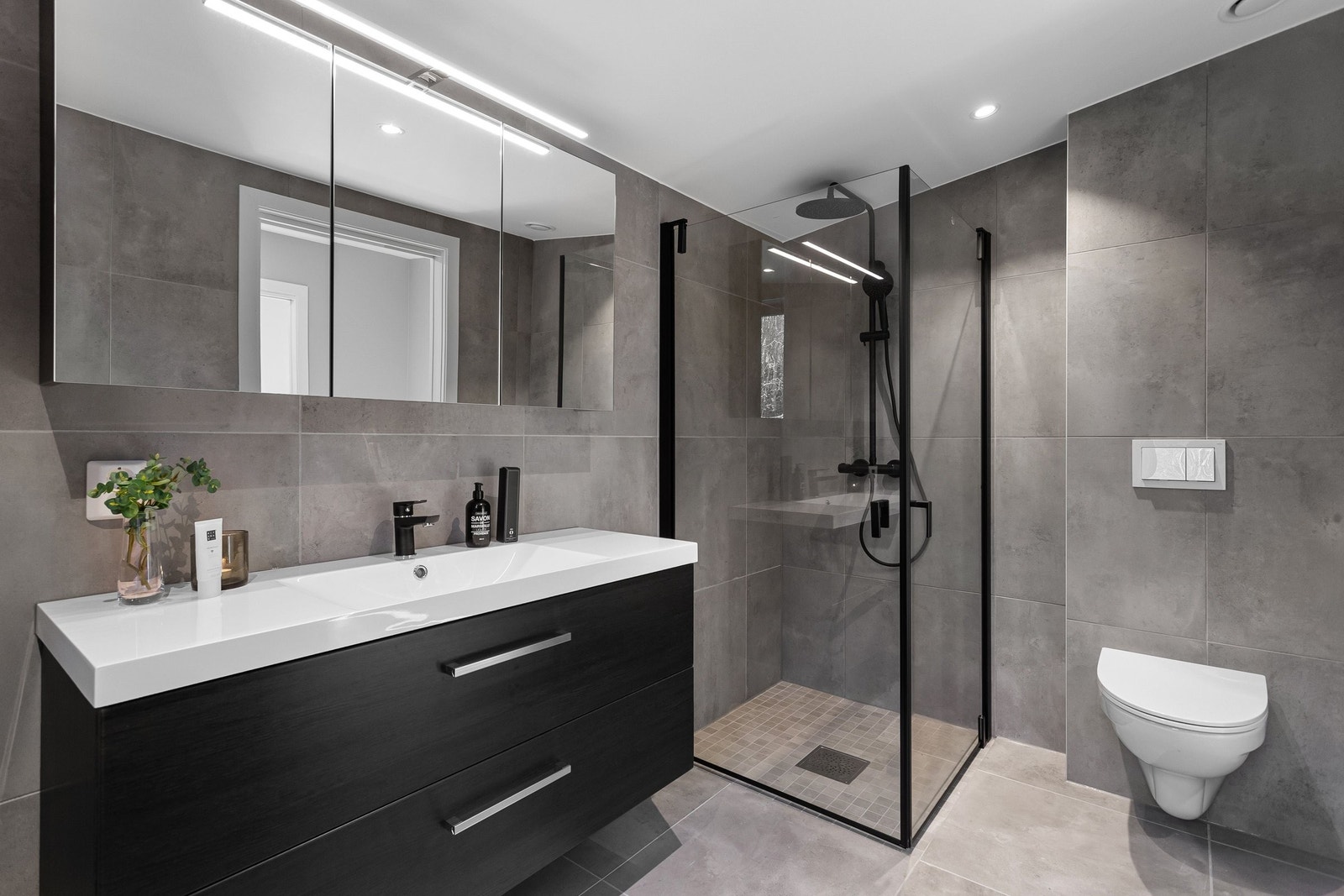 Badet har en moderne, sort innredning med gjennomførte detaljer som gir et stilrent og helhetlig inntrykk. Galleribilde