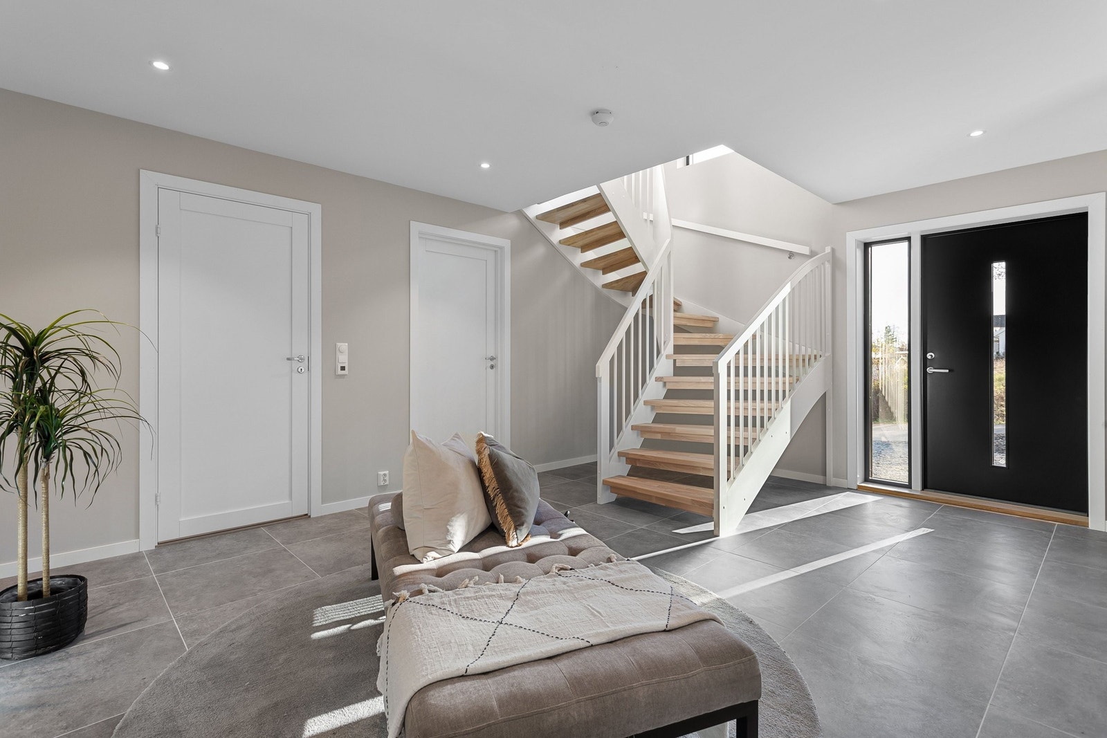 Velkommen inn til en lys og romslig entré med flislagt gulv, gulvvarme og effektiv bruk av downlights i taket. Galleribilde