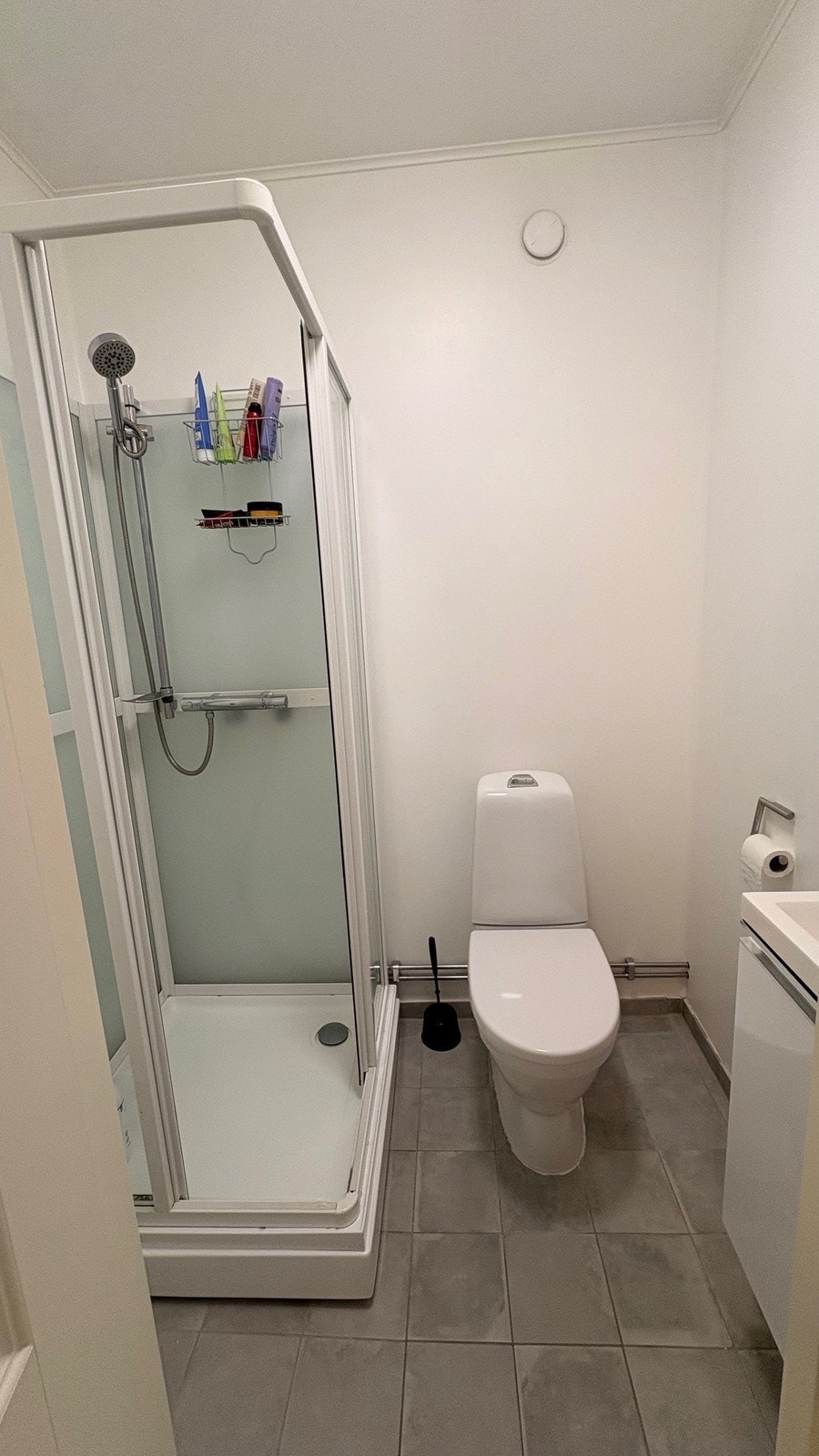 Flislagt bad(gulv) med varmekabler. Dusjkabinett, toalett og servant med underskap. Galleribilde