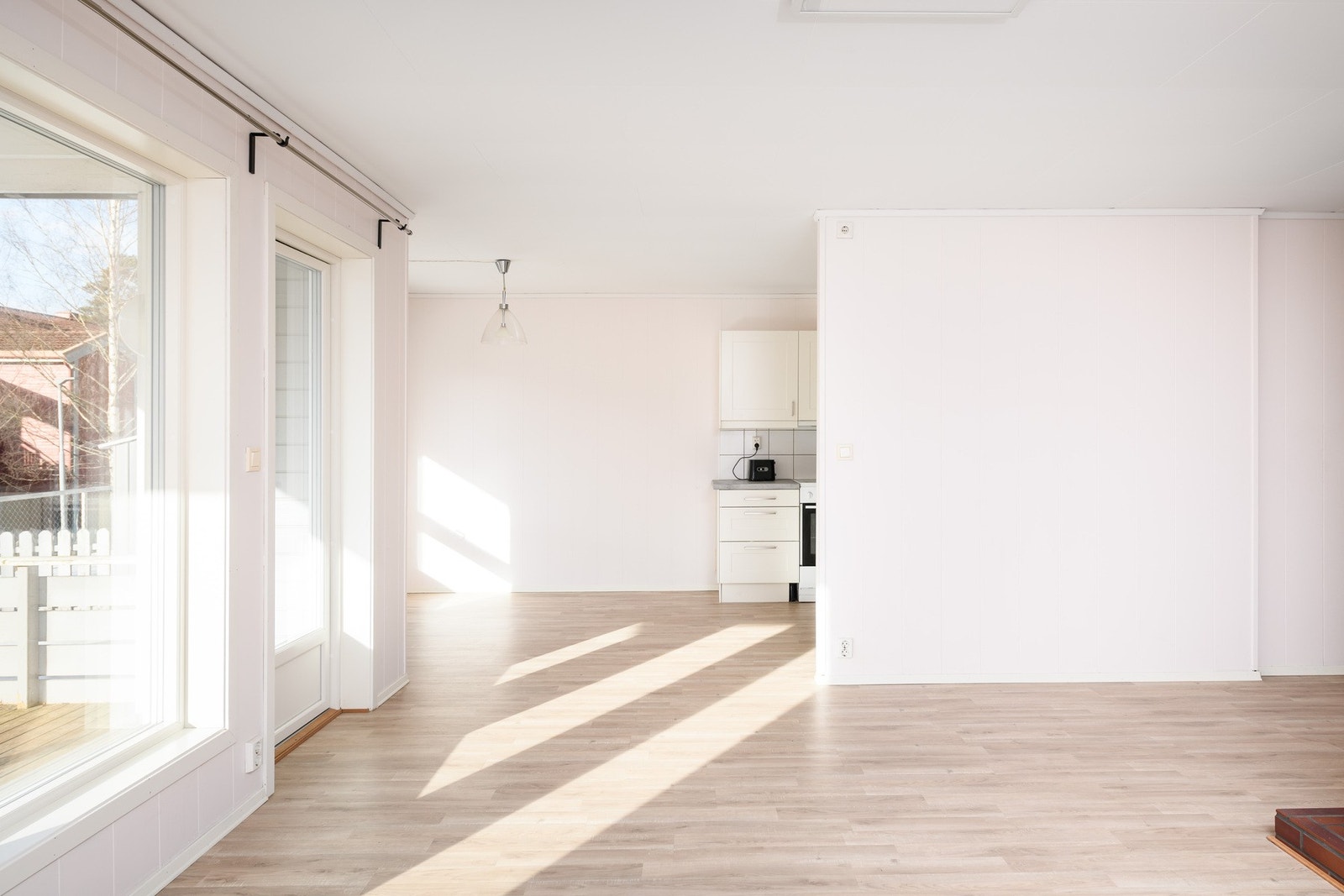 Dagslyset som strømmer inn via store vestvendte vinduer gjenspeiles fint i de lysmalte overflatene i allrommet. Galleribilde