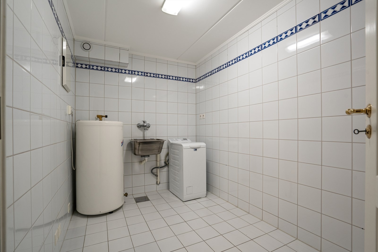 Vaskerom med skyllekar og opplegg for vaskemaskin. Det er installert varmekabler i gulv. Galleribilde