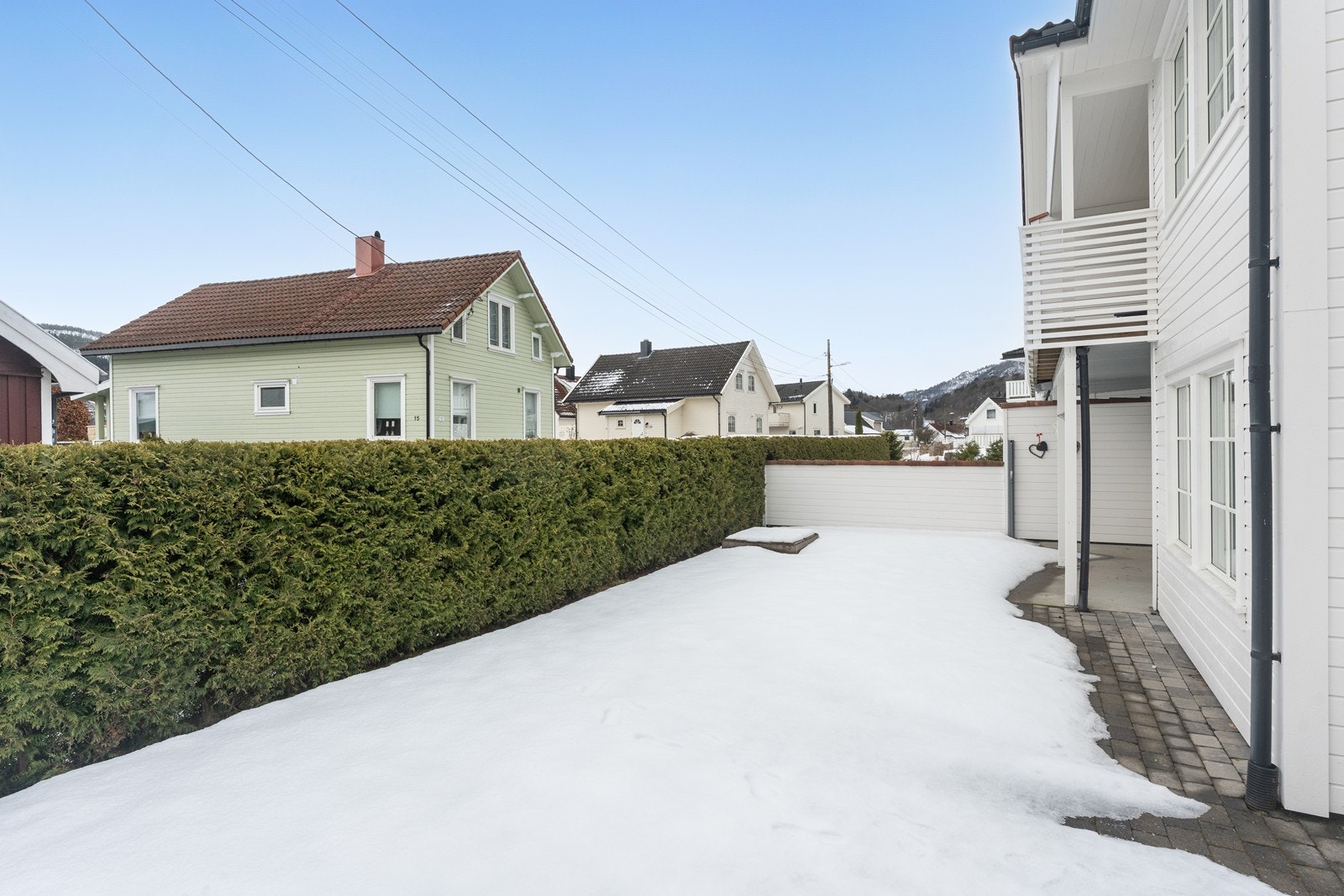 Støpt uteplass, og delvis hellebelagt, samt plen. Fint avskjermet med hekk og skillevegg. Galleribilde