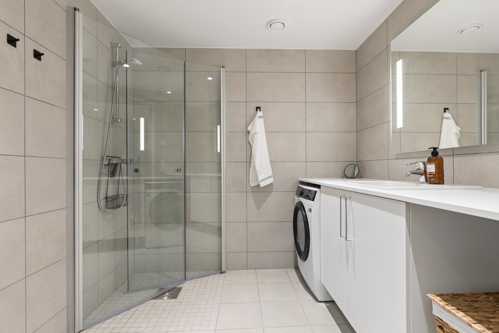 Romslig baderom med servant, dusjhjørne med innfellbare dører og vegghengt toalett. Galleribilde