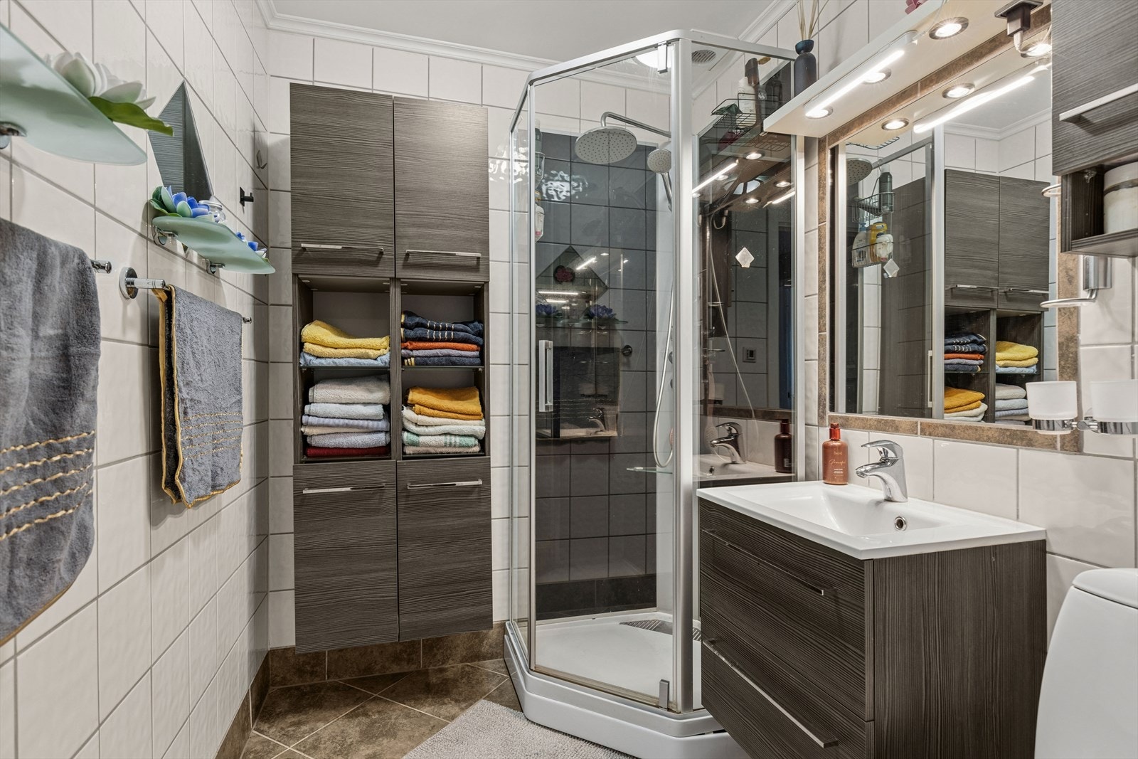 Baderommet er flislagt og utstyrt med dusjkabinett og servantinnredning. Galleribilde