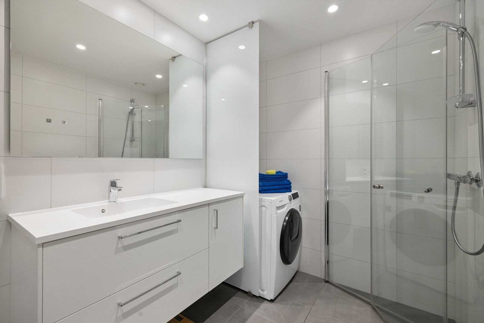 Badet er utstyrt med servant med underskap, vegghengt toalett, dusjhjørne og opplegg for vask/tørk. Galleribilde