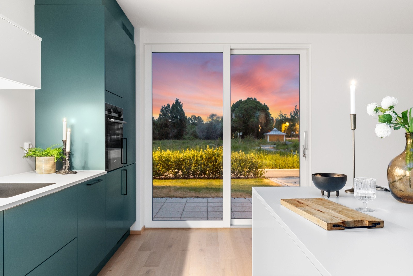 Stemningsbilde fra kjøkken med hyggelig utsikt mot privat hellelagt uteareal Galleribilde