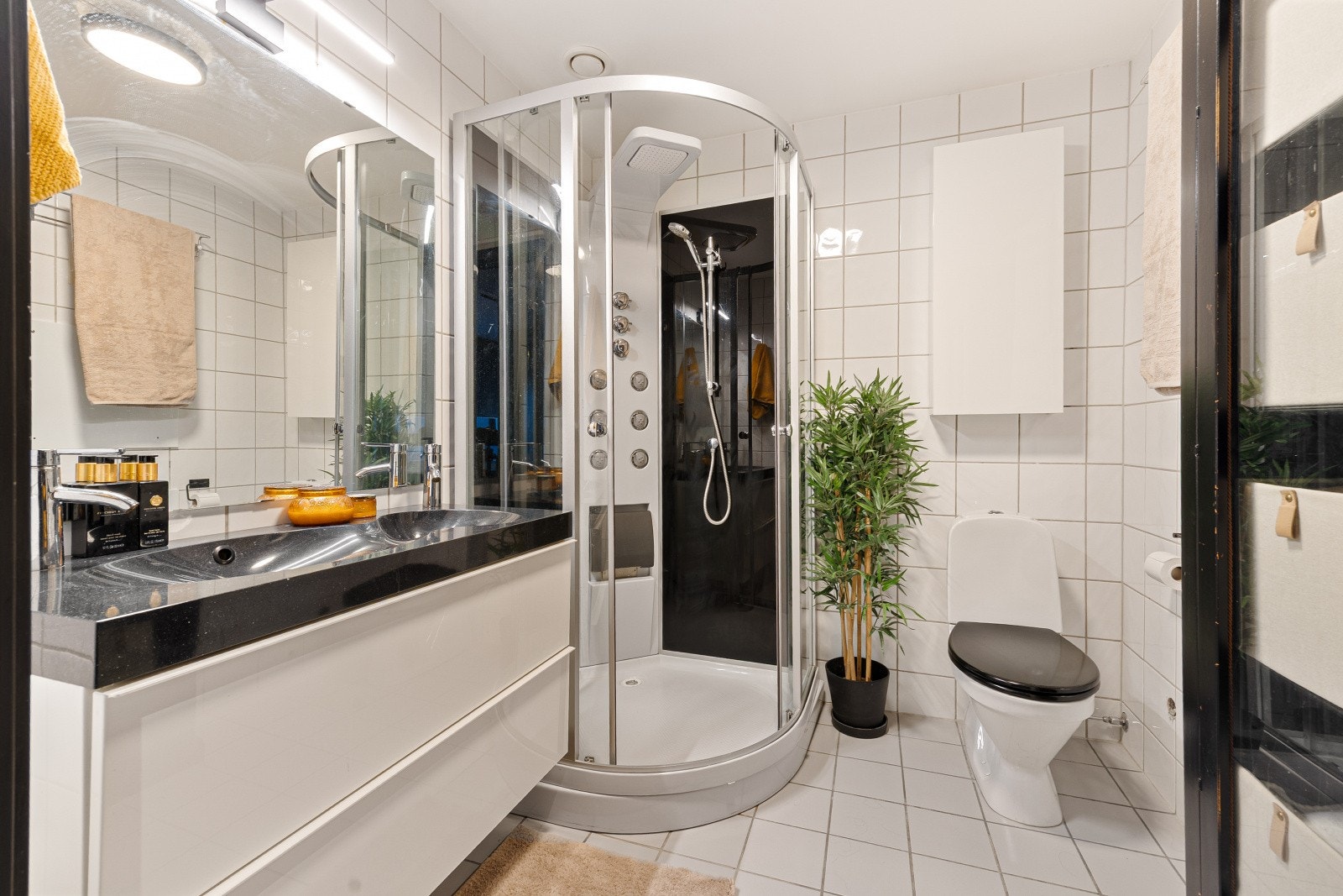 Flislagt baderom med dusjkabinett, servantinnredning og toalett. Galleribilde