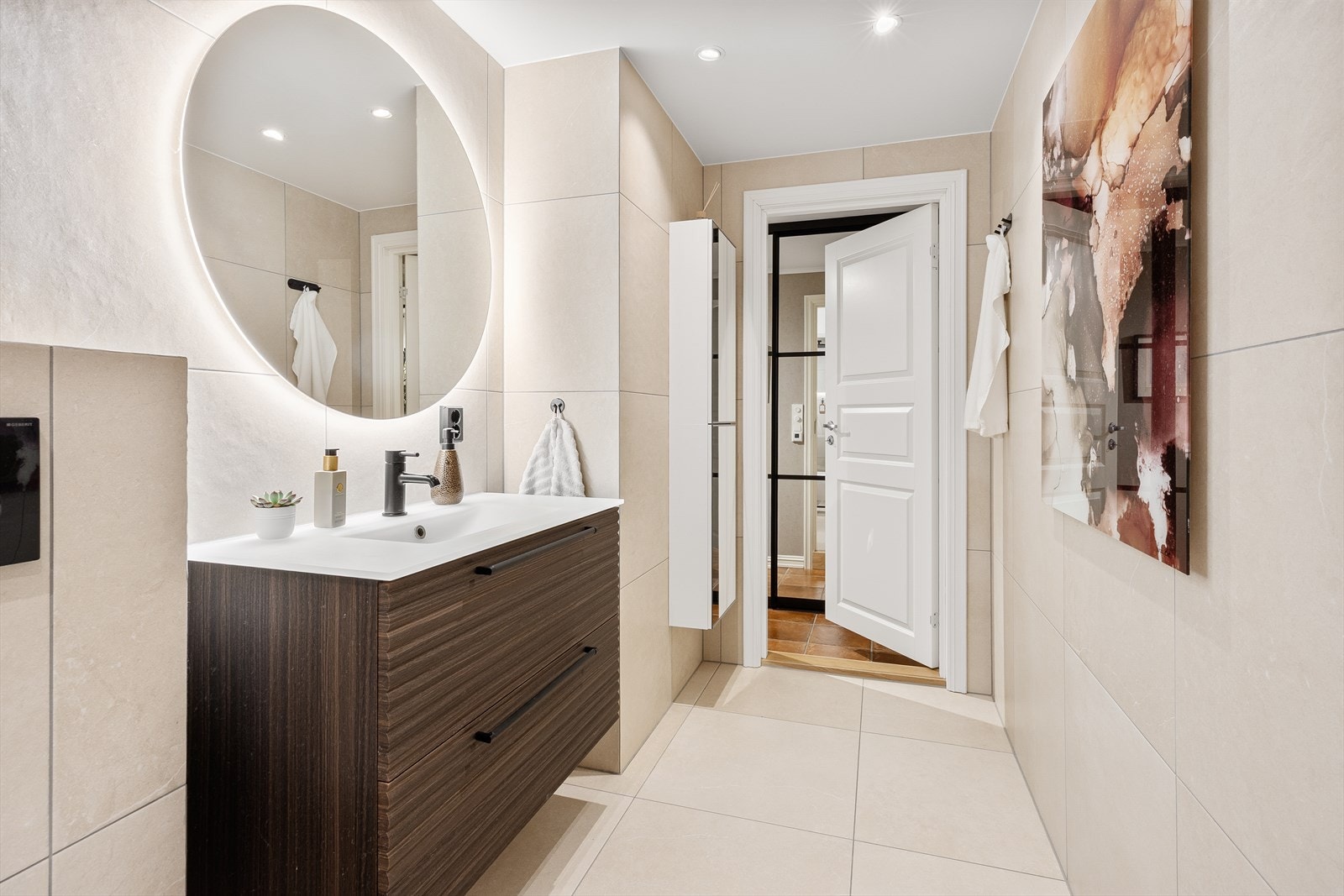 Flislagte vegger og gulv med varmekabler. Nedsenket dusjsone med glassvegg. Vegghengt WC og moderne servantinnredning med speil og belysning. Downlights i himling. Galleribilde