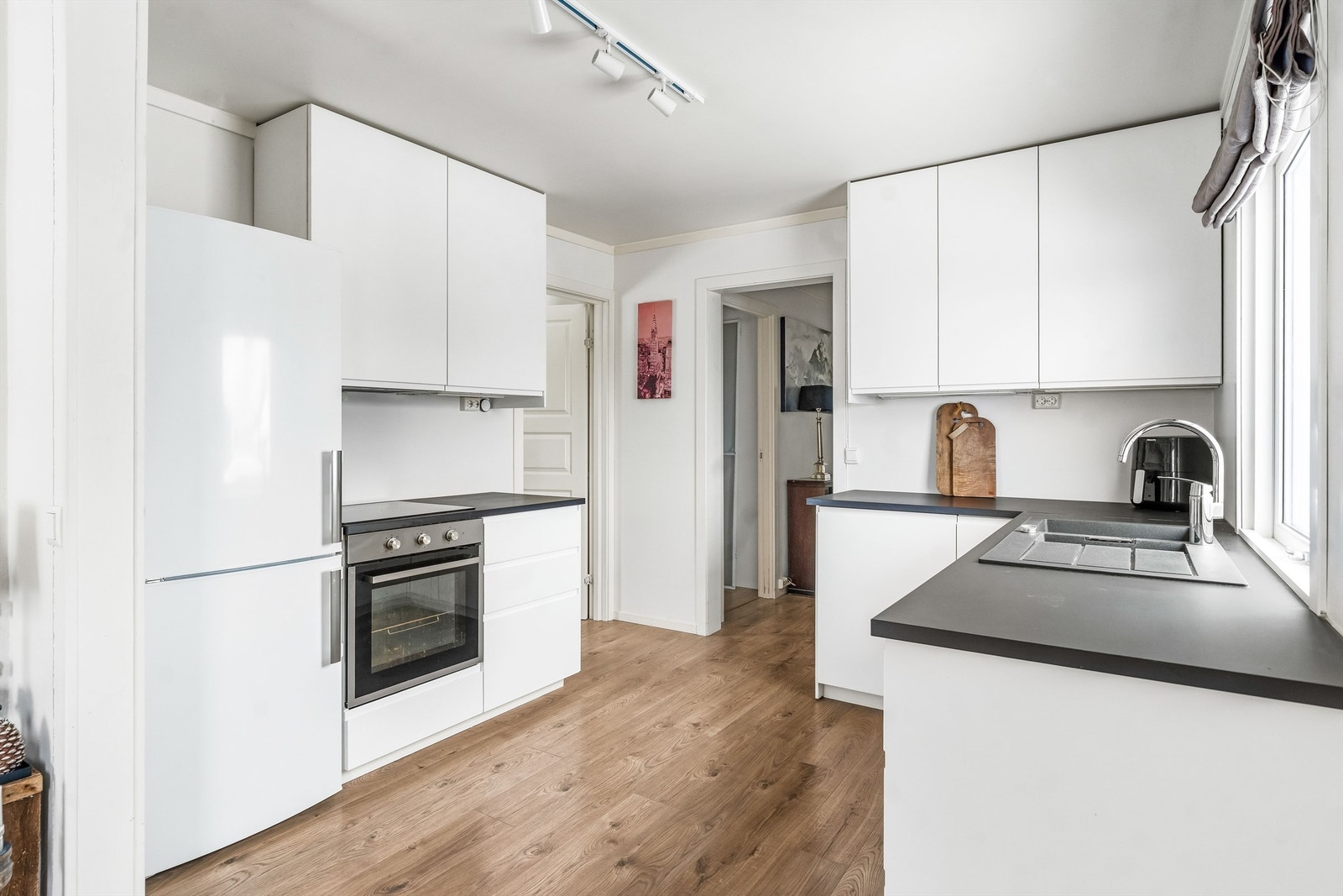 Overskap med belysning under og ventilator tilkoblet avtrekkskanal, laminert benkeplate med kompositt skyllekum og oppvaskkum med ett-greps armatur, samt induksjons koketopp Galleribilde