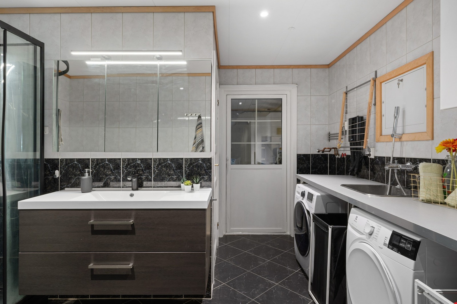 Badet har dusjkabinett, vask med speil, og opplegg for vaskemaskin og tørketrommel. Galleribilde
