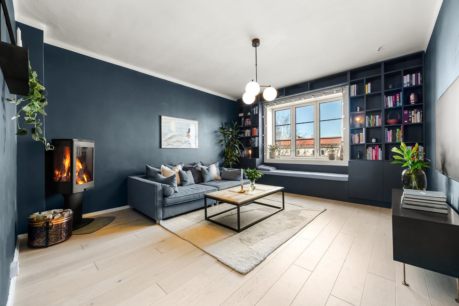 Stor og innbydende stue. Stuen er innredet med en plassbygget hylleløsning med benk som pent rammer inn det store vinduet. Galleribilde