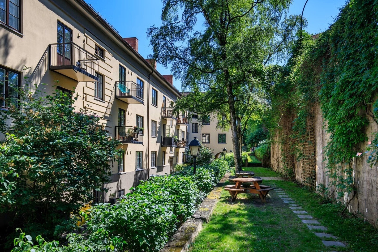 Tomten er pent opparbeidet med asfalterte og brosteinsbelagte internveier. Variert beplantning, sykkelstativer, skur, lekeplass og sittegrupper med grill. Galleribilde