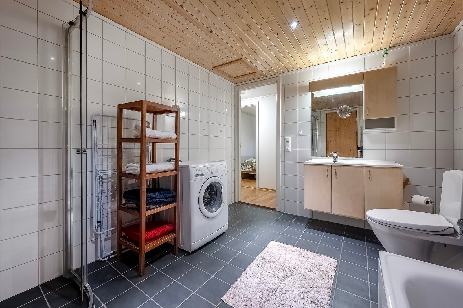 Romslig bad med dusjhjørne, baderomsinnredning og opplegg for vaskemaskin. Galleribilde