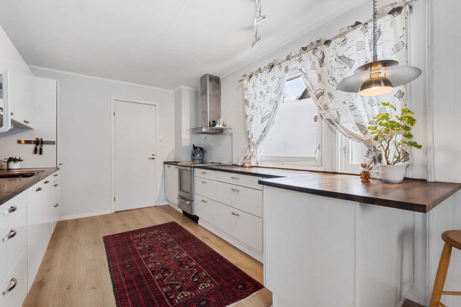 Tidløst og koselig kjøkken med generøs skap- og benkeplass. Innredningen består av slette, hvite fronter. Galleribilde