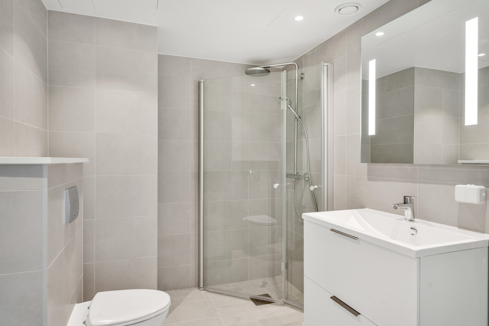 Servantinnredning med skuffer og stort speil med LED-lys. Opplegg for vaskemaskin/tørketrommel. Galleribilde