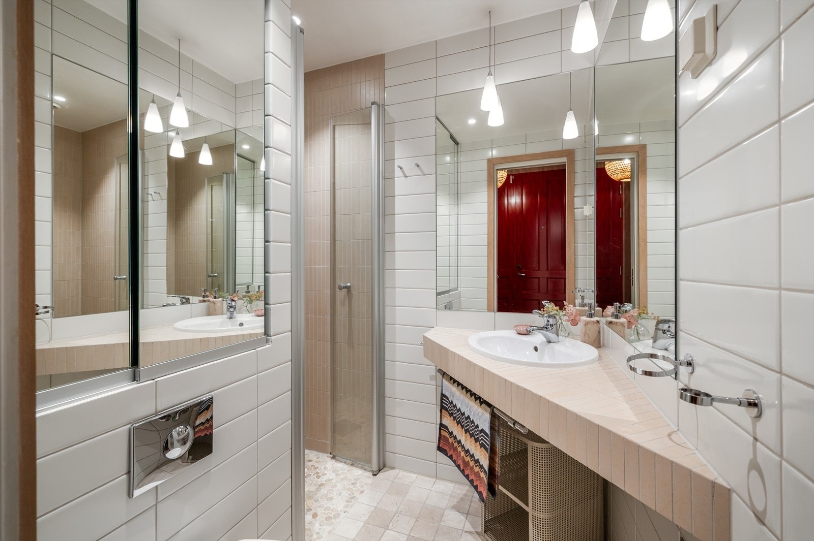 Flislagt baderom innredet med vegghengt toalett, servant nedsenket i flislagt benk og dusjhjørne med svingbar glassdør. Galleribilde