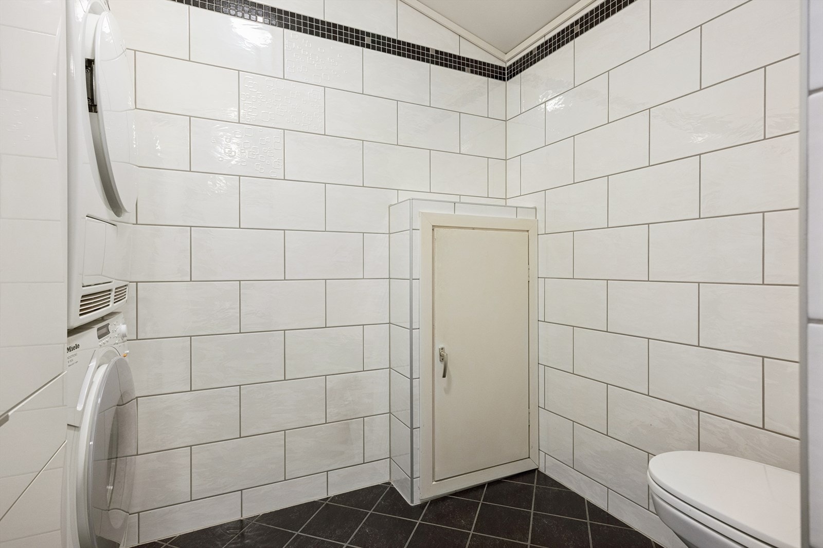 Praktisk vaskeromsavdeling på 3,7 m² i tilknytning til badet. Opplegg til vaskemaskin og tørketrommel, vegghengt klosett og luke til varmtvannsbereder. Galleribilde