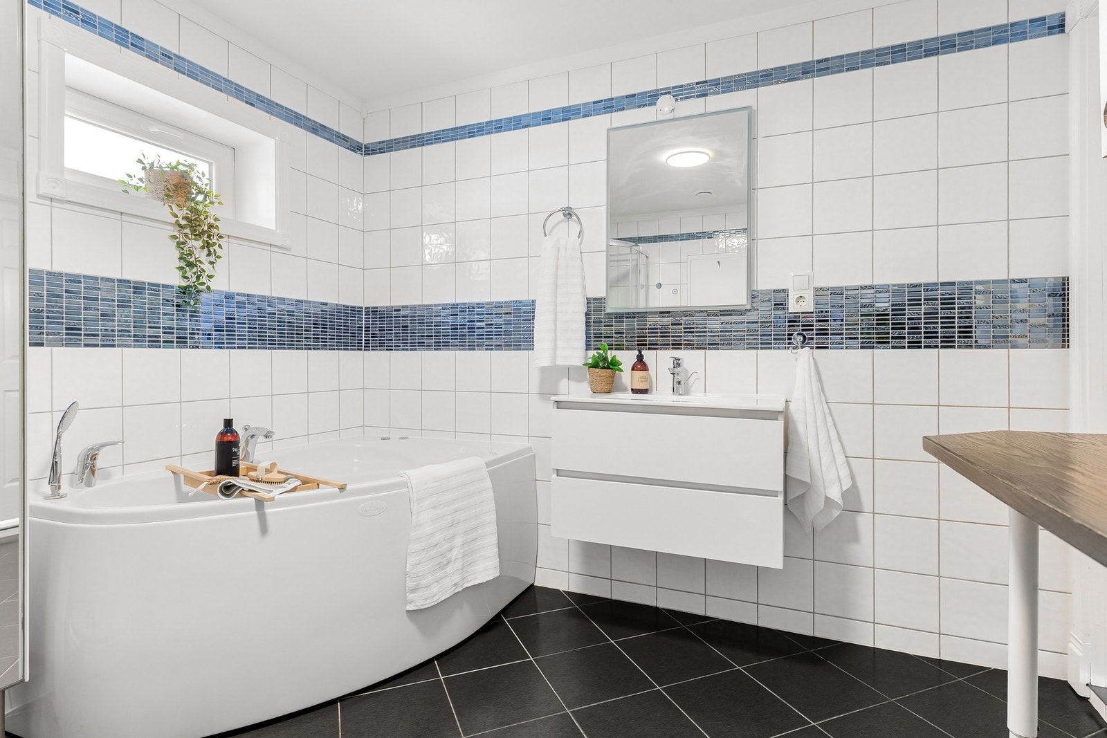 Flislagt bad med servant, badekar, dusjkabinett, toalett og opplegg for vaskemaskin. Galleribilde