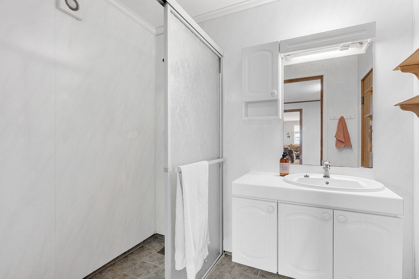 Vegger på badet er kledd med baderomsplater og er innredet med dusjnisje med skyvedør, samt servant med skapinnredning. Galleribilde