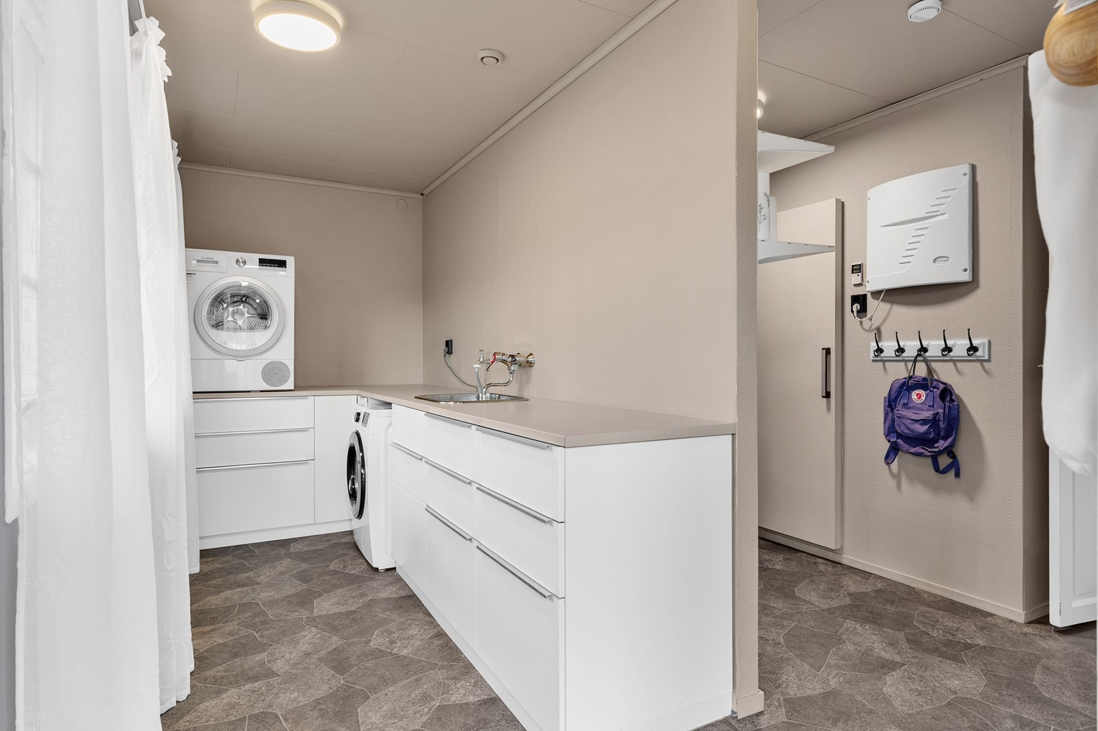 Praktisk vaskerom med vaskeromsinnredning, utslagsvask og opplegg for vaskemaskin. Kjølerom med tilknytning til vaskerom. Galleribilde