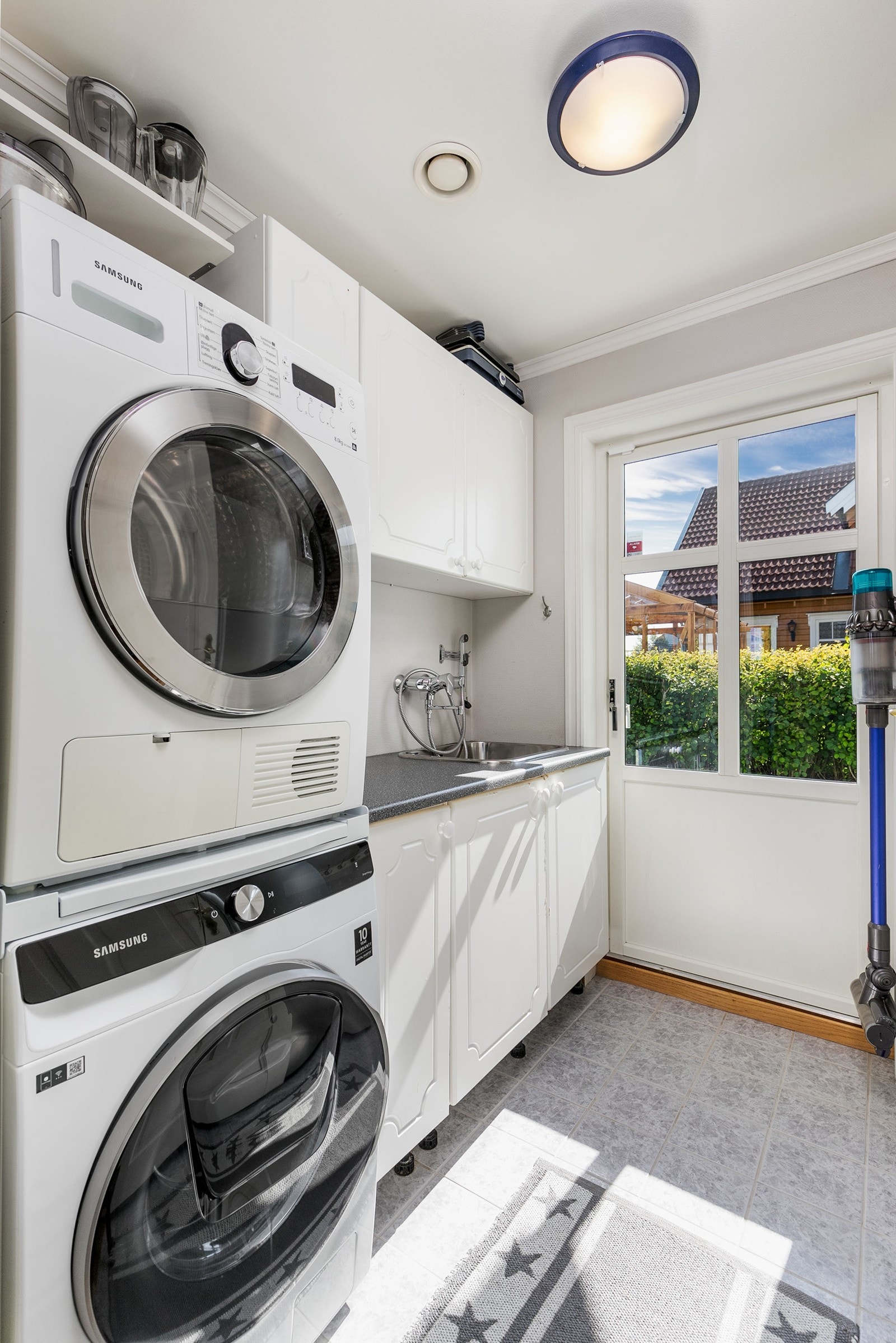 Praktisk vaskerom i boligens 1. etasje. Vaskerom med flislagt gulv og vegger kledd med tapetserte overflater på plater. Sluk i plast. Galleribilde