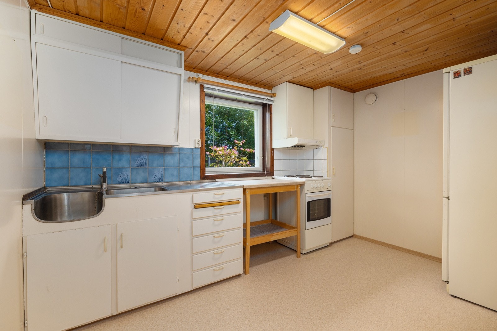 Kjøkkenet i denne etasjen har innredning med laminerte skrog og glatte, hvite fronter. laminer benkeplate og benkebeslag med kjøkkenkum. Fliser og belysning over benkeplate. Kjøkkenet har plass til frittstående komfyr og kjøleskap. Galleribilde