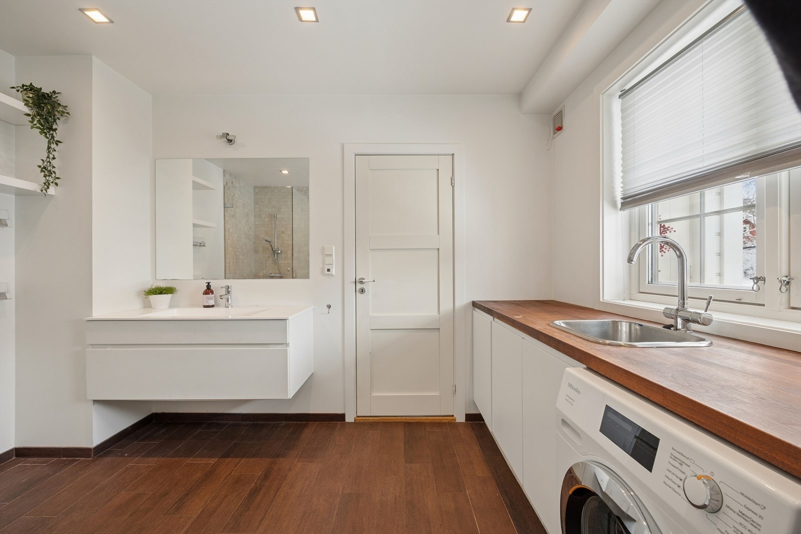 Badet har veggmontert toalett, servant og et dusjhjørne med glassvegger. Galleribilde