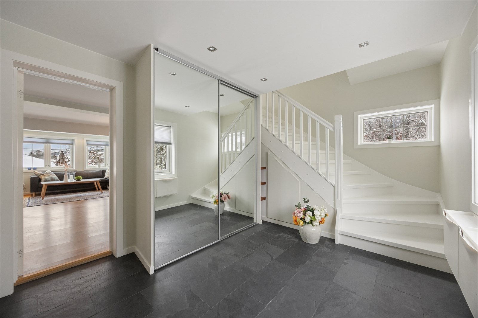 Romslig hall med flislagt gulv og god oppbevaringsplass i skyvedørsgarderobe med speilfronter. Galleribilde