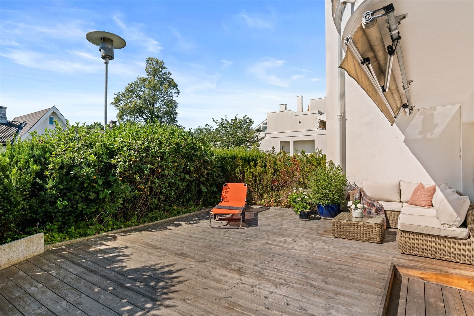 Fra stuen er det adkomst til en sydvendte markterrassen på ca. 30 m². Terrassen er utstyrt med markise, utelys og stikkontakt.
Selgers sommerbilde av den solrike terrassen Galleribilde