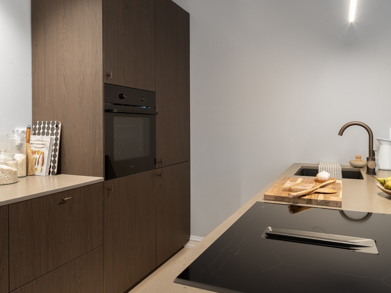 Mørke laminerte fronter i imitert tre og grå benkeplater i kompositt. Galleribilde