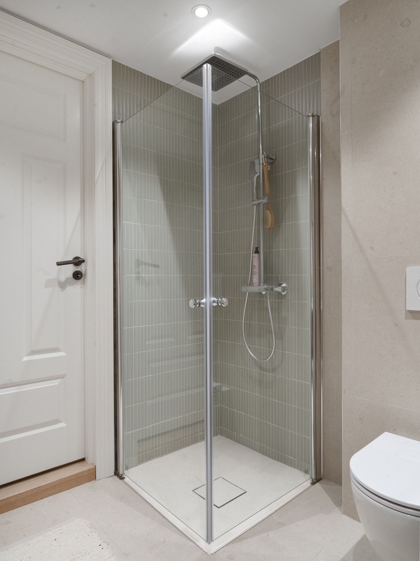 Dusjhjørne rett på gulv med nedfliset dusjsone, innfellbare glassdører, dusjbatteri, regndusj og hånddusj. Galleribilde