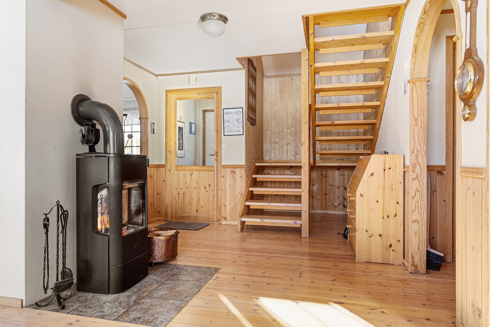 I stue/gang står en god peisovn, ildstedet ble oppgradert i 2024. Her leder en åpen tretrapp opp til loftsetasjen. Galleribilde