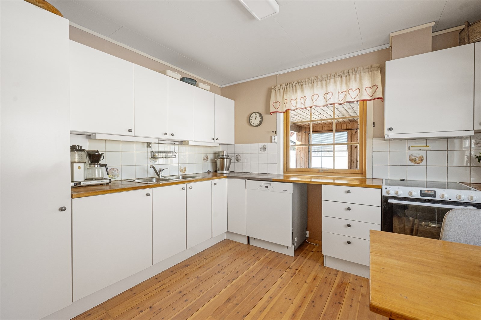 Funksjonelt kjøkkeninnredning med glatte fronter, benkeplate i tre og fliser over benken. Galleribilde