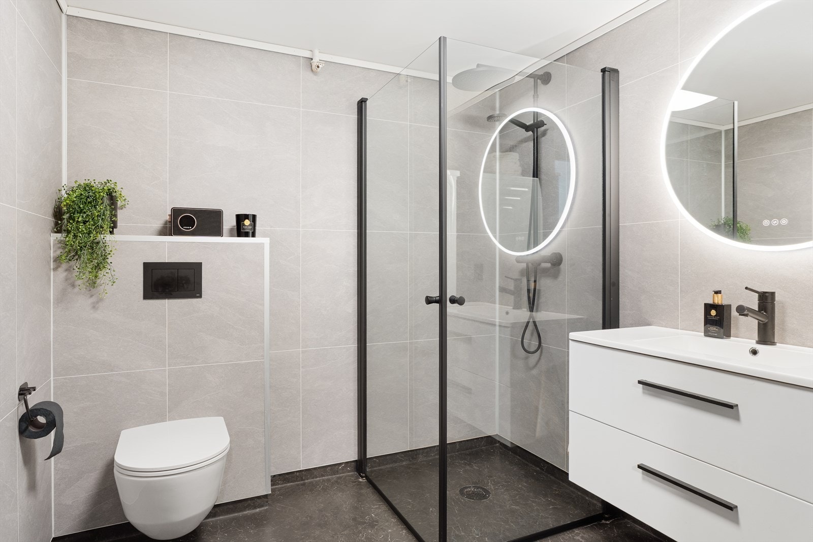 Lekkert bad/vaskerom som ble fagmessig pusset opp i 2023. Badet er innredet med dusjhjørne med sort dusjgarnityr, seksjon med servant, veggspeil med lys, samt vegghengt toalett med integrert lekkasjesikring. Galleribilde