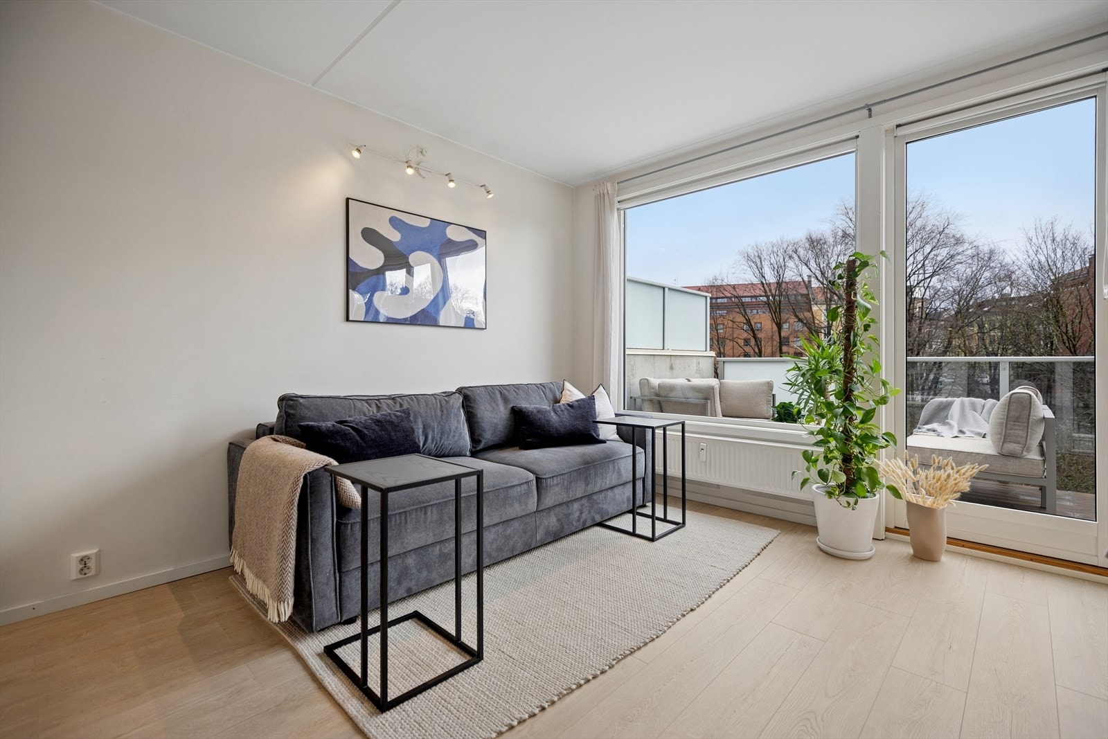 Store vindusflater og balkongdør slipper inn rikelig med naturlig lys og gir stuen en lys og luftig atmosfære. Galleribilde