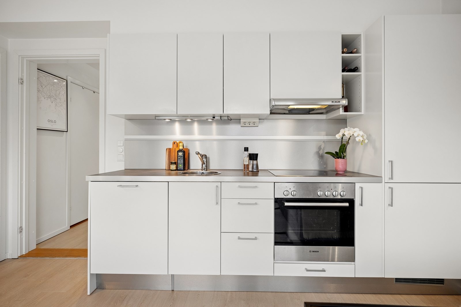 Kjøkkenet fra byggeåret 2010 har en hvit, mattlakkert innredning med glatte fronter og en laminatbenkeplate med nedfelt, rund stålvask. Galleribilde