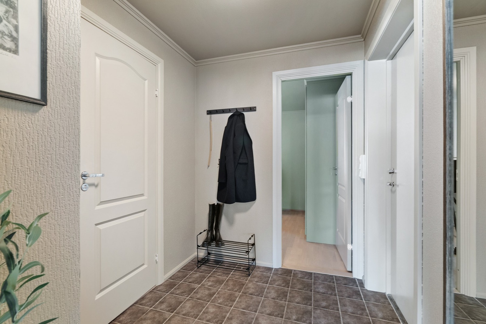 Entréen har en enkel og funksjonell innredning med praktiske løsninger som vegghengte knagger og skohylle. Galleribilde